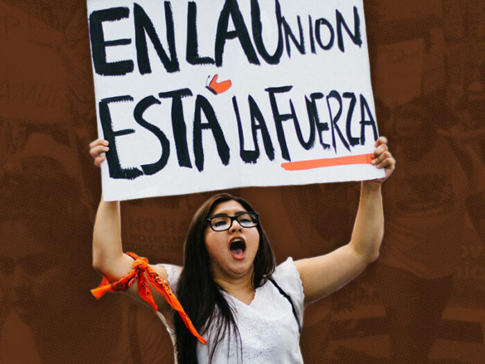 Woman rising a sign that reads En la unión está la fuerza (Strentgh is within unity)