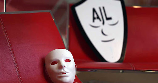 a white mask on a red seat, the AJL logo is in the background